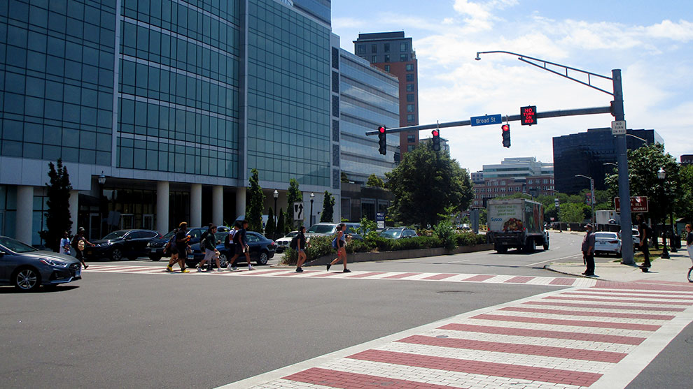 Busy intersection with people crossing at crosswalk and a red stop signal