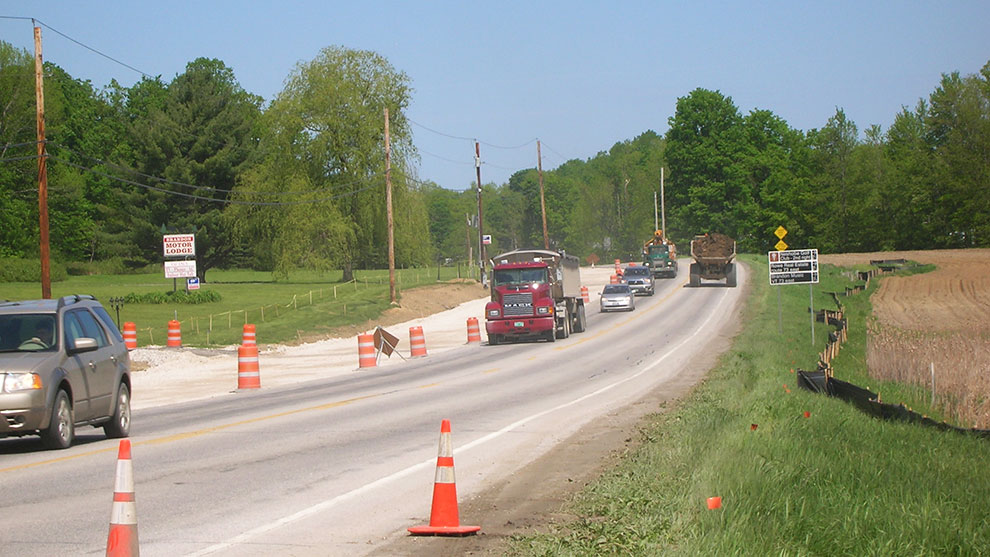 view of road with cars, trucks and traffic cones during construction