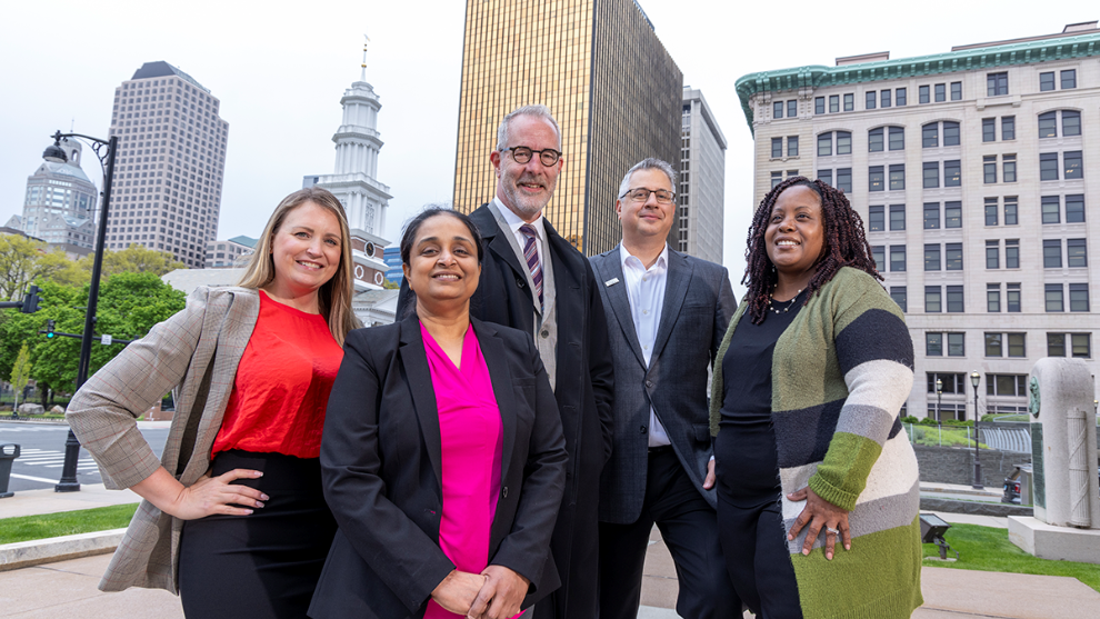 HBJ PHOTO | STEVE LASCHEVER - Fuss & O’Neill senior leaders stand in front of their future home, the Gold Building in downtown Hartford. (From left): VP and Marketing Dir. Kathy Nanowski, IT manager Krithiga Sridar, CEO and President Kevin Grigg, Sr. VP and Regional Manager Craig Lapinski, and Exec. Asst. Tatia Lewis-Hayes.