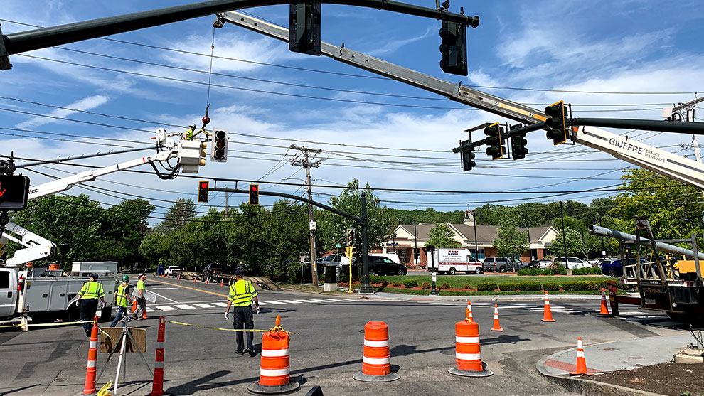 Construction working standing in road near cones while traffic engineering improvements are happening